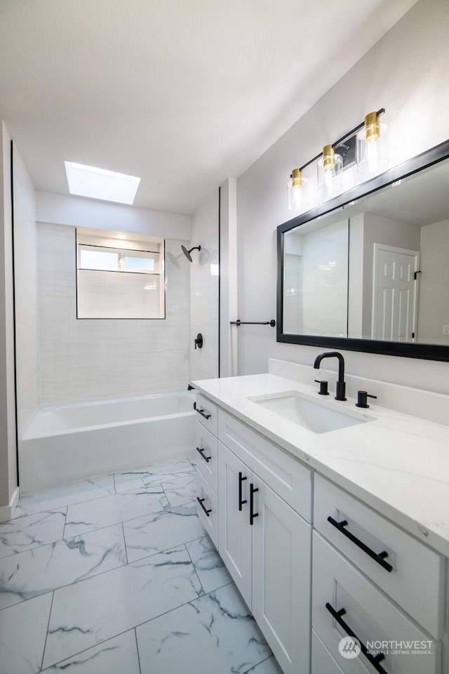 bathroom with vanity, a skylight, and tiled shower / bath