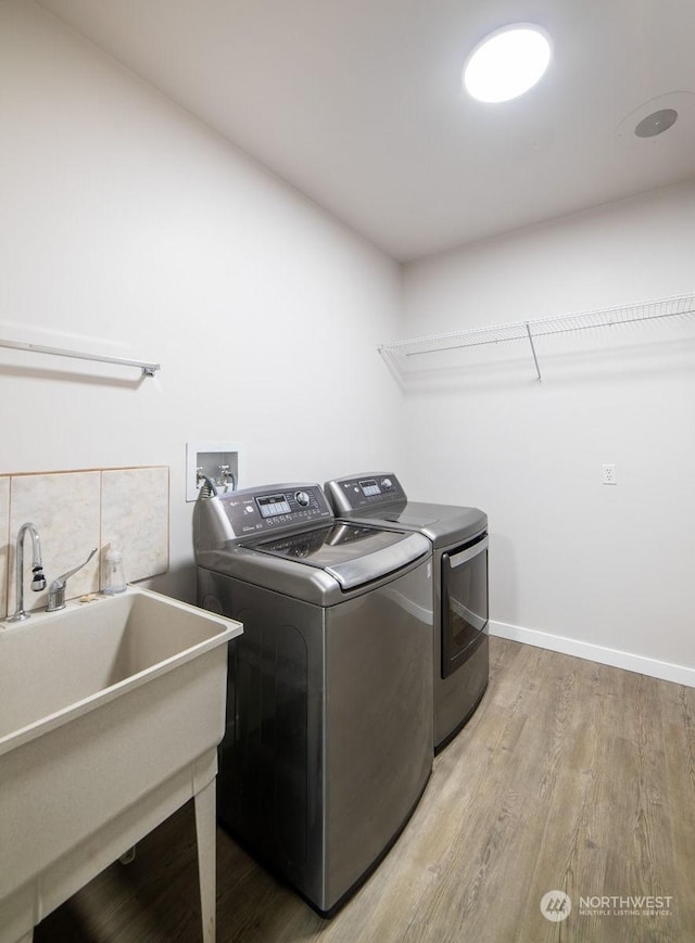 laundry area featuring sink, light hardwood / wood-style floors, and washer and dryer