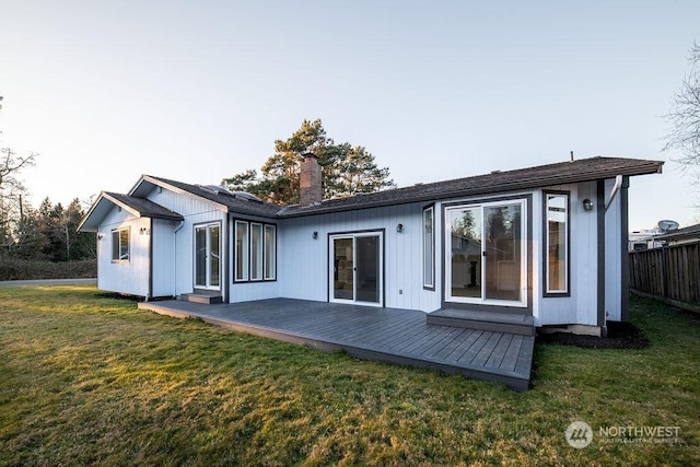 rear view of house with a wooden deck and a lawn