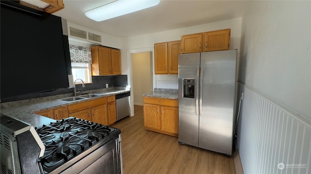 kitchen with stainless steel appliances, sink, and light hardwood / wood-style flooring