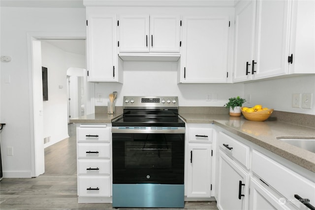 kitchen with stainless steel range with electric stovetop, light hardwood / wood-style flooring, light stone countertops, and white cabinets