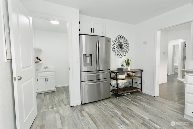 kitchen with light hardwood / wood-style flooring, stainless steel fridge, and white cabinets