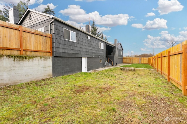 rear view of house with a yard and an outdoor fire pit