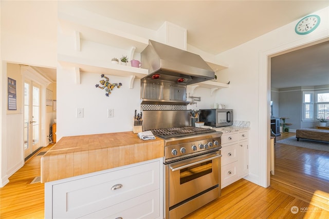 kitchen featuring island exhaust hood, butcher block counters, white cabinets, and high end range