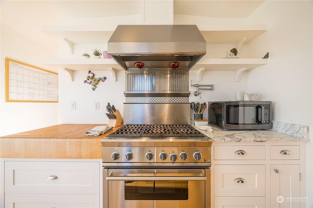 kitchen featuring white cabinetry, island range hood, stainless steel appliances, and butcher block counters