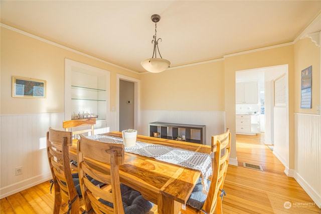 dining space featuring ornamental molding and light hardwood / wood-style flooring