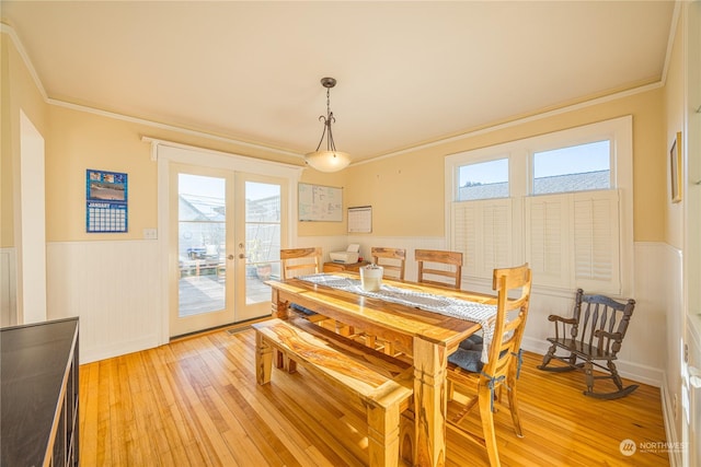 dining space featuring crown molding, light wood-type flooring, and french doors