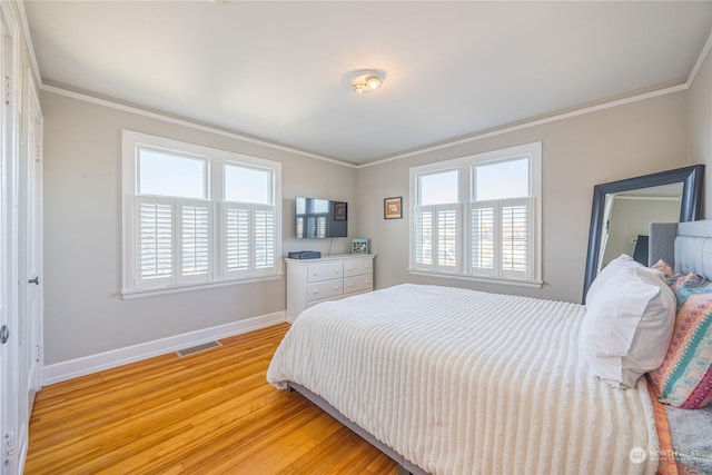 bedroom featuring multiple windows, crown molding, and light wood-type flooring