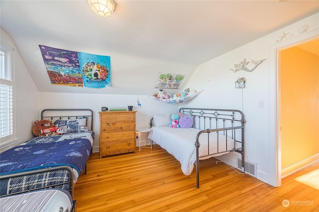 bedroom with lofted ceiling and wood-type flooring