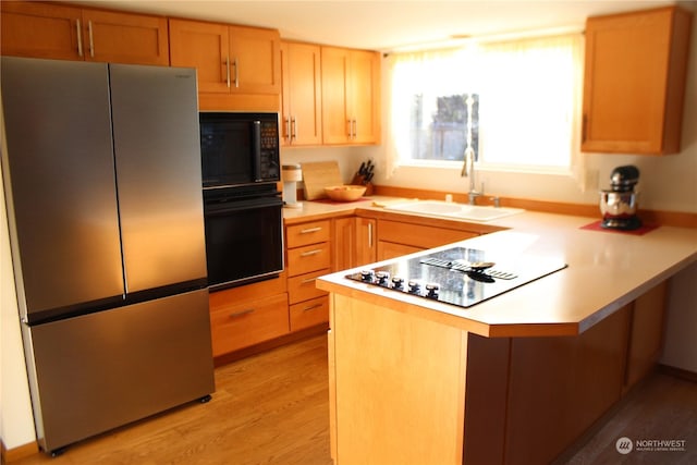 kitchen featuring light hardwood / wood-style floors, sink, black appliances, and kitchen peninsula