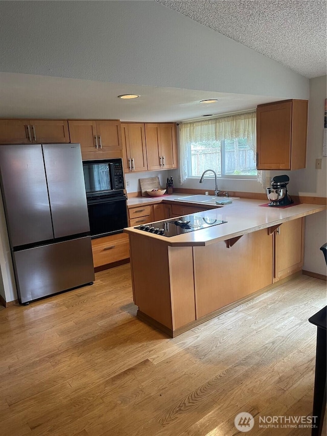 22507 SE 304th Pl, Black Diamond, WA 98010 - kitchen with black appliances, a sink, lofted ceiling, a peninsula, and light wood-style floors