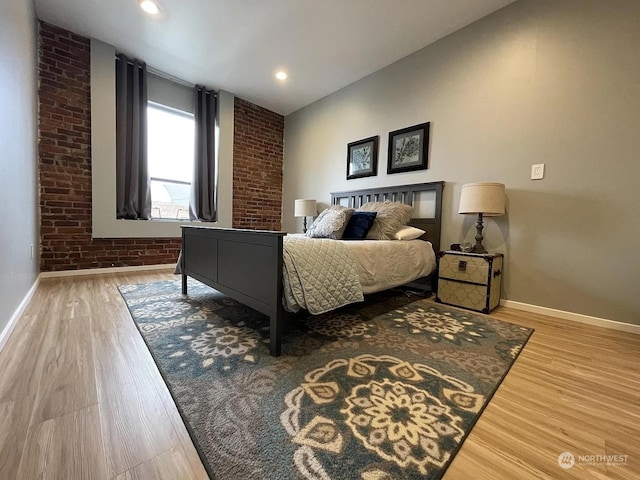 bedroom featuring wood-type flooring and brick wall