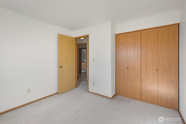 unfurnished bedroom with light carpet and a closet