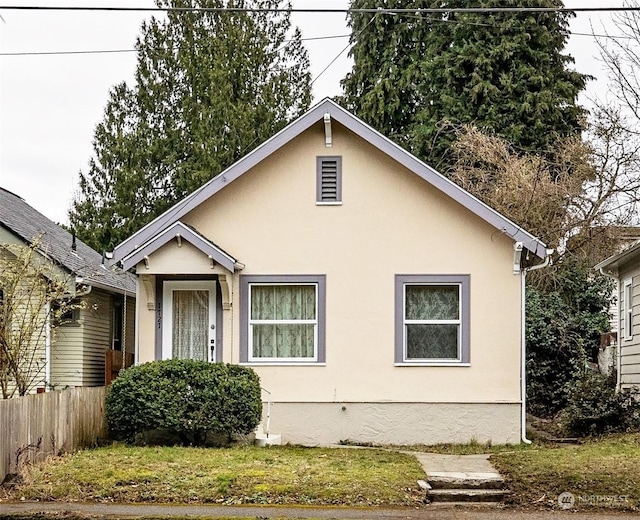 bungalow-style house with fence and stucco siding