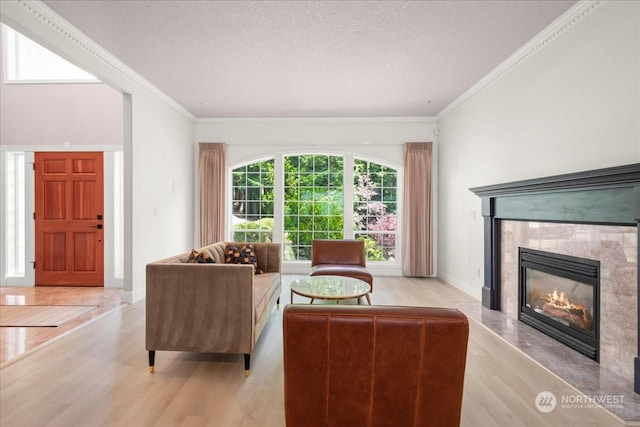 living room with ornamental molding, a high end fireplace, a textured ceiling, and light hardwood / wood-style floors