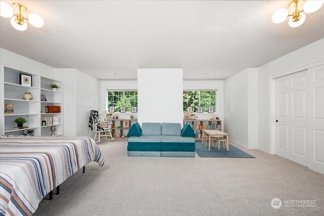 carpeted bedroom featuring a textured ceiling and an inviting chandelier