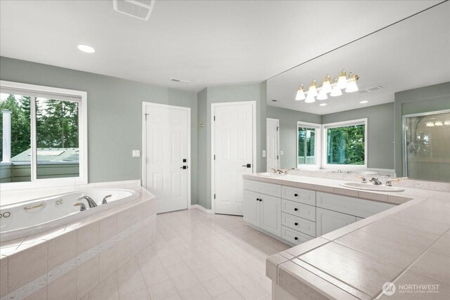 bathroom featuring plenty of natural light, vanity, and tiled tub