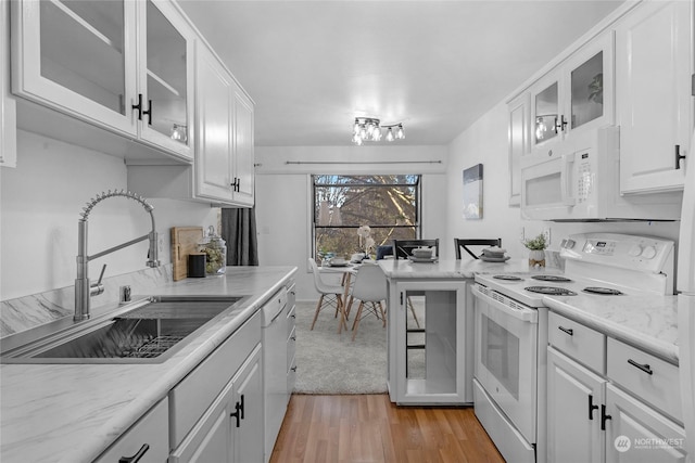 kitchen featuring white cabinetry, sink, light stone counters, light hardwood / wood-style floors, and white appliances