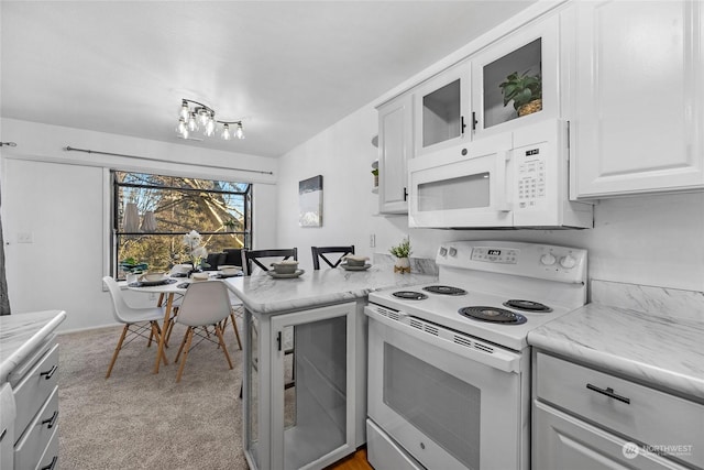 kitchen featuring white appliances, white cabinetry, light stone counters, light carpet, and kitchen peninsula