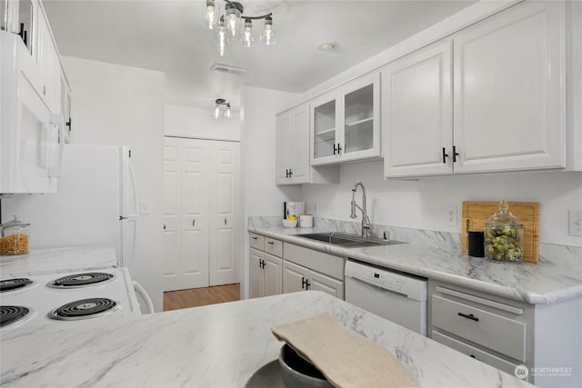 kitchen featuring light stone countertops, sink, white cabinets, and white appliances