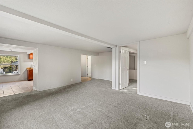 carpeted empty room with tile patterned flooring and baseboards