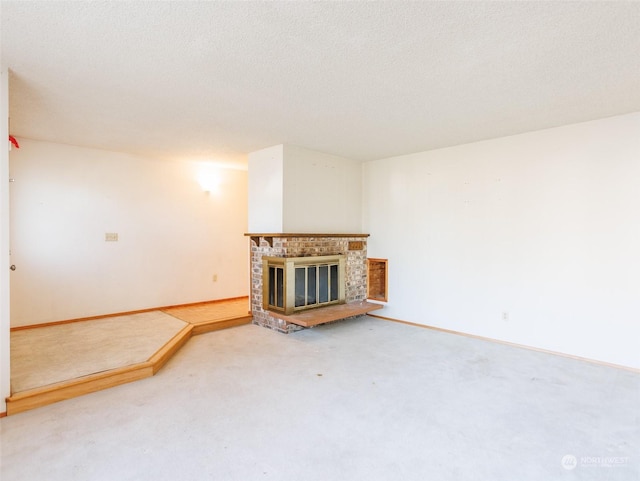 unfurnished living room with carpet flooring, a brick fireplace, and a textured ceiling