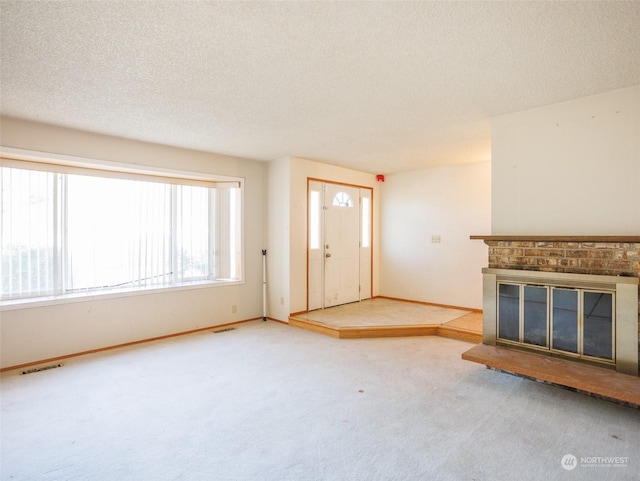 unfurnished living room featuring a brick fireplace, carpet flooring, and a textured ceiling