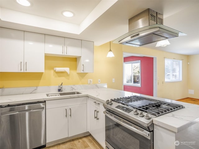 kitchen featuring sink, appliances with stainless steel finishes, white cabinetry, island range hood, and light stone countertops