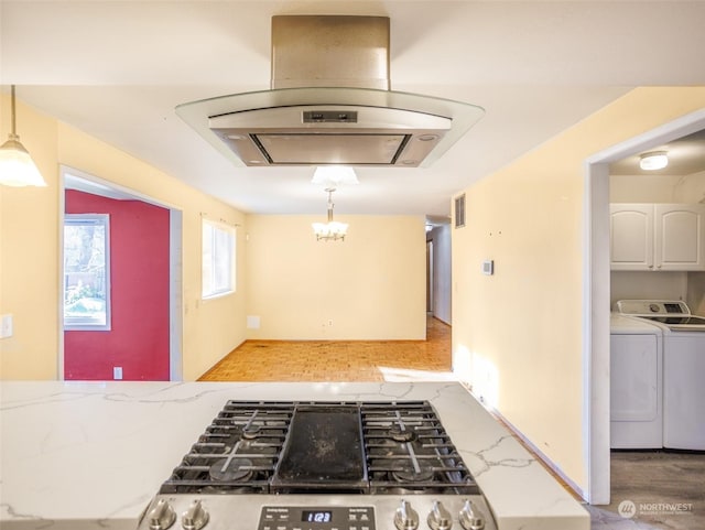 kitchen with island exhaust hood, decorative light fixtures, gas stove, and washing machine and clothes dryer