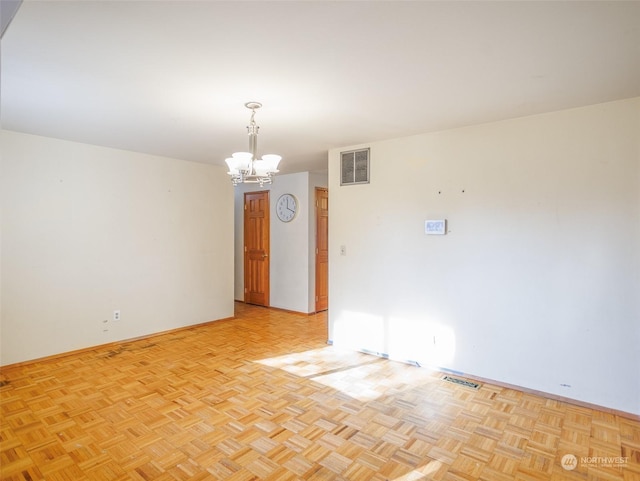 empty room with light parquet flooring and a chandelier