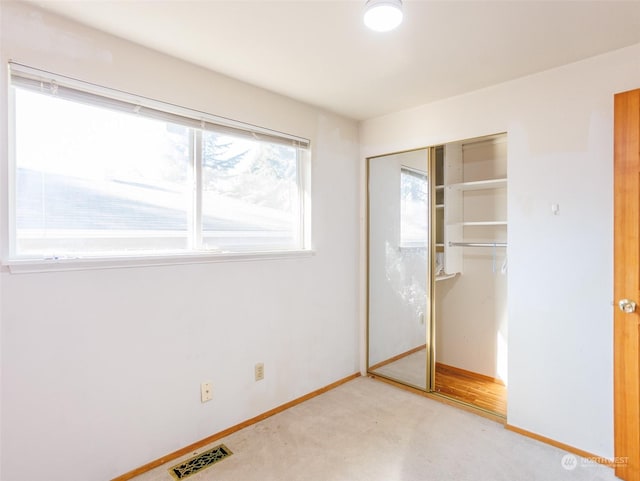 unfurnished bedroom with light colored carpet and a closet