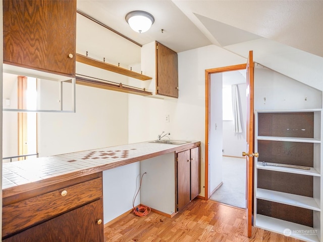 kitchen with tile counters, light hardwood / wood-style floors, and sink