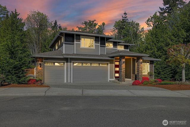 prairie-style house with stone siding, an attached garage, and concrete driveway