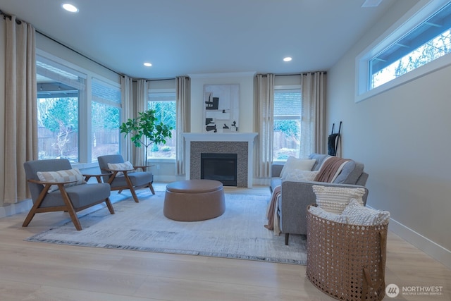 living room with recessed lighting, a tile fireplace, a wealth of natural light, and wood finished floors