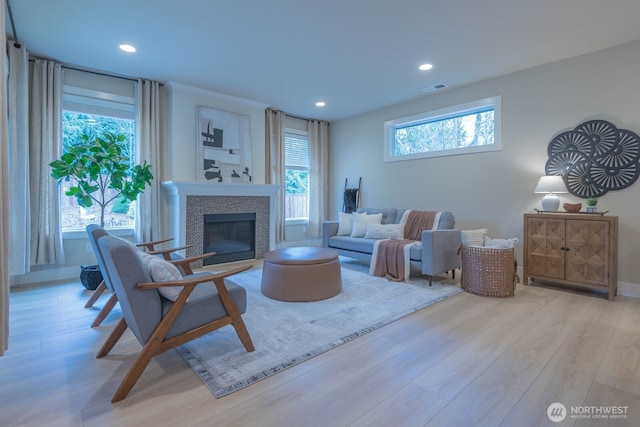 living area with light wood finished floors, a tile fireplace, visible vents, and recessed lighting