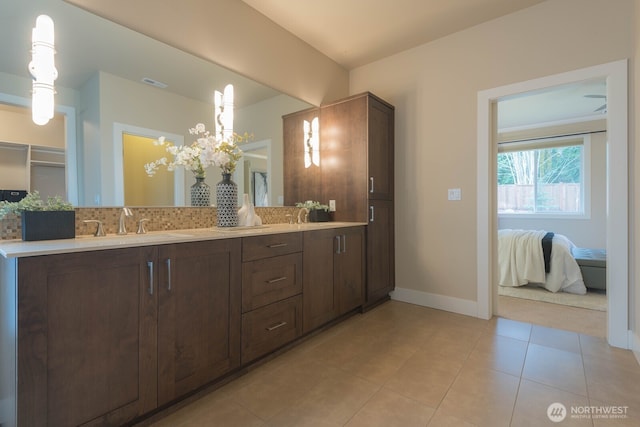 ensuite bathroom featuring double vanity, tasteful backsplash, visible vents, baseboards, and tile patterned floors