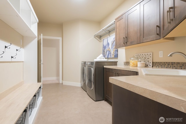 laundry room featuring light floors, cabinet space, a sink, and washing machine and clothes dryer