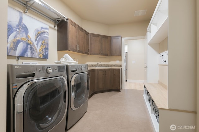 washroom featuring light floors, visible vents, washing machine and dryer, a sink, and laundry area