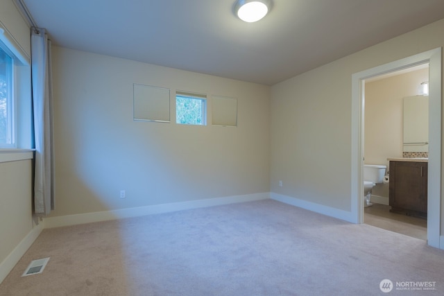 unfurnished bedroom featuring baseboards, connected bathroom, visible vents, and carpet flooring