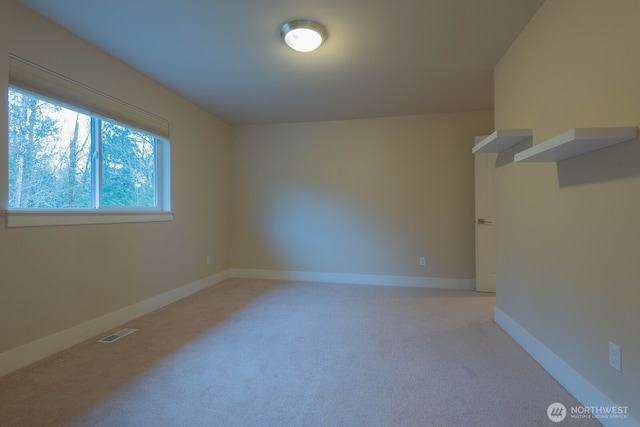 spare room featuring light carpet, visible vents, and baseboards