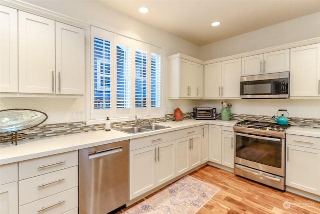 kitchen featuring white cabinetry, appliances with stainless steel finishes, sink, and light hardwood / wood-style flooring