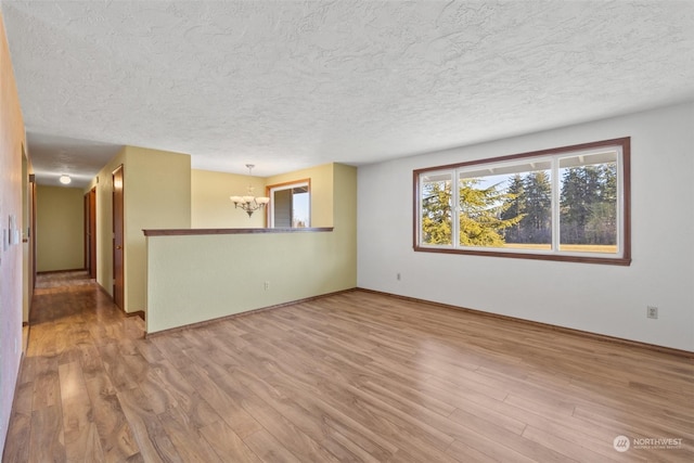 interior space with a textured ceiling, a notable chandelier, and light wood-type flooring