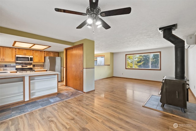 kitchen featuring appliances with stainless steel finishes, a wall mounted AC, light hardwood / wood-style flooring, and a wood stove