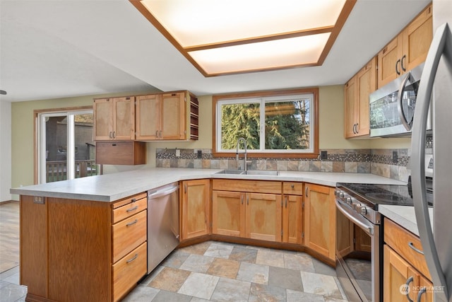 kitchen featuring stainless steel appliances, sink, decorative backsplash, and kitchen peninsula