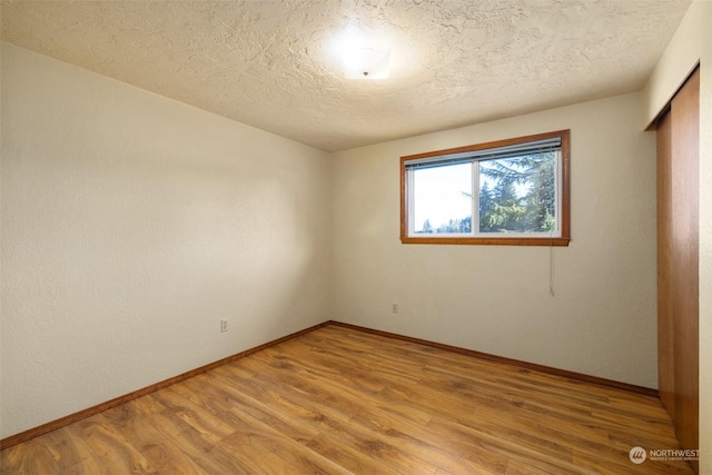 empty room featuring light hardwood / wood-style flooring and a textured ceiling