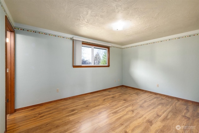 spare room with a textured ceiling and light wood-type flooring