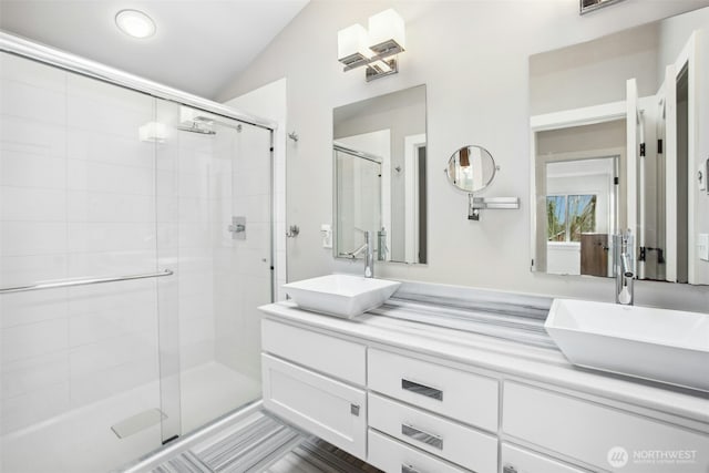 bathroom with double vanity, a sink, and a shower stall