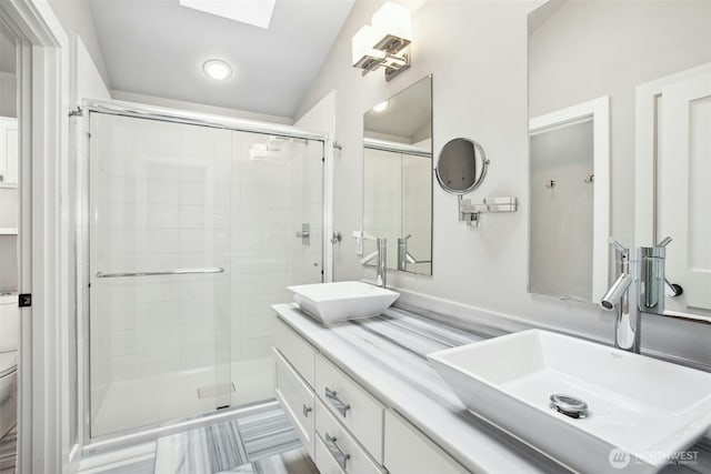 full bathroom with toilet, a stall shower, double vanity, and a sink