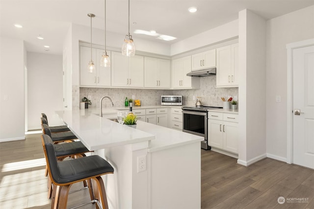 kitchen featuring pendant lighting, appliances with stainless steel finishes, kitchen peninsula, and white cabinets