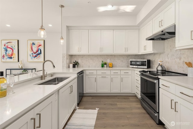 kitchen featuring pendant lighting, sink, appliances with stainless steel finishes, white cabinets, and decorative backsplash